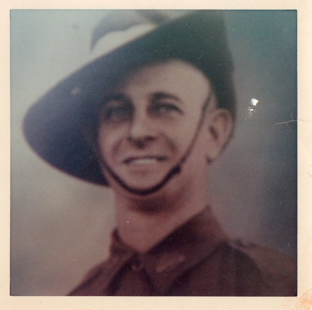 A smiling young soldier in a slouch hat and AIF uniform, head-and-shoulders studio portrait.
