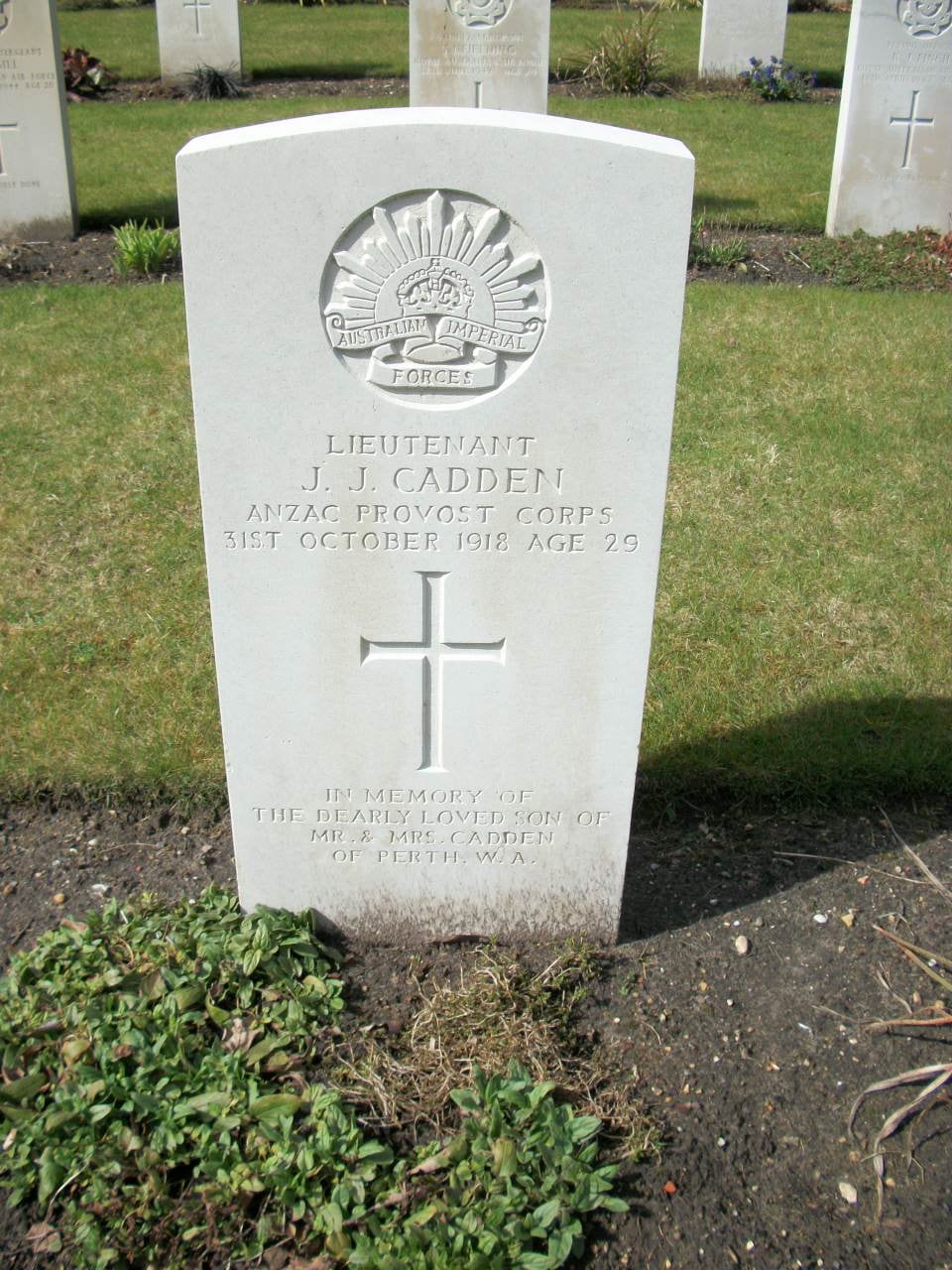 White Commonwealth war grave headstone with the Rising Sun badge, reading Lieutenant J. J. Cadden, Anzac Provost Corps, 31st October 1918, age 29, with a cross and the inscription In memory of the dearly loved son of Mr & Mrs Cadden of Perth W.A.