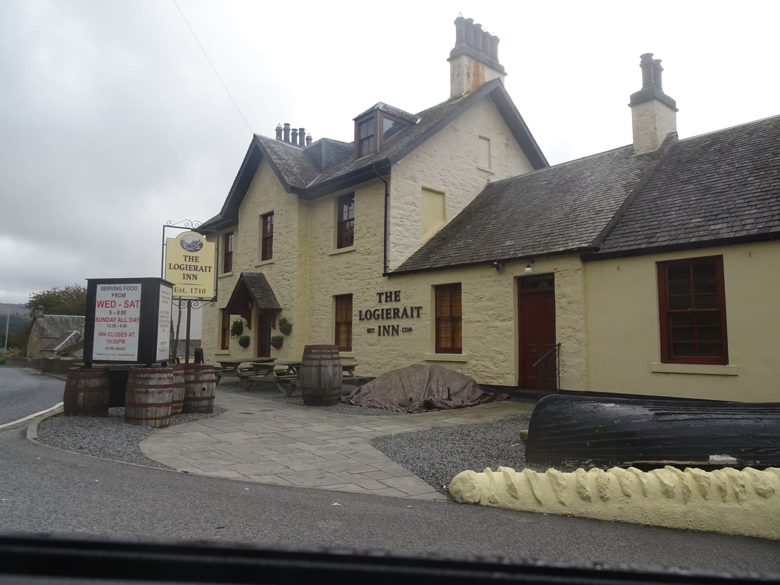 A cream-painted two-storey Scottish country inn with dormer windows, a sign reading "The Logierait Inn, Est. 1710," on a quiet village street.